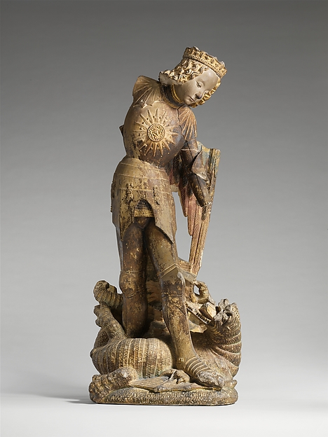 Carved figure of the winged Saint Michael holding a broken weapon.